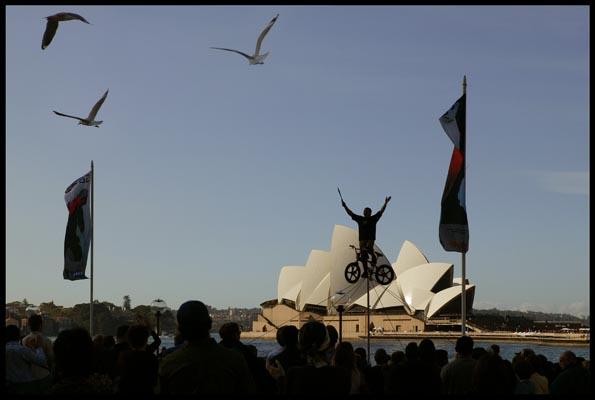 busker at Circular Quay with a mono cycle act, entertaining a large crowd
